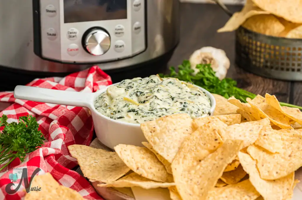 Bowl of spinach dip&mdash;one of the best easy summer dips&mdash;with chips and parsley.