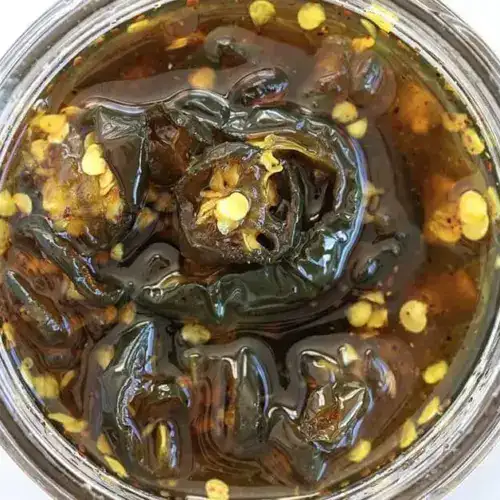 A jar of candied jalape&ntilde;os&mdash;perfect for easy summer dips, seeds visible.