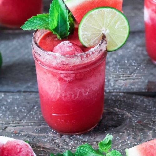 Red frozen watermelon drink in a jar with lime and mint.