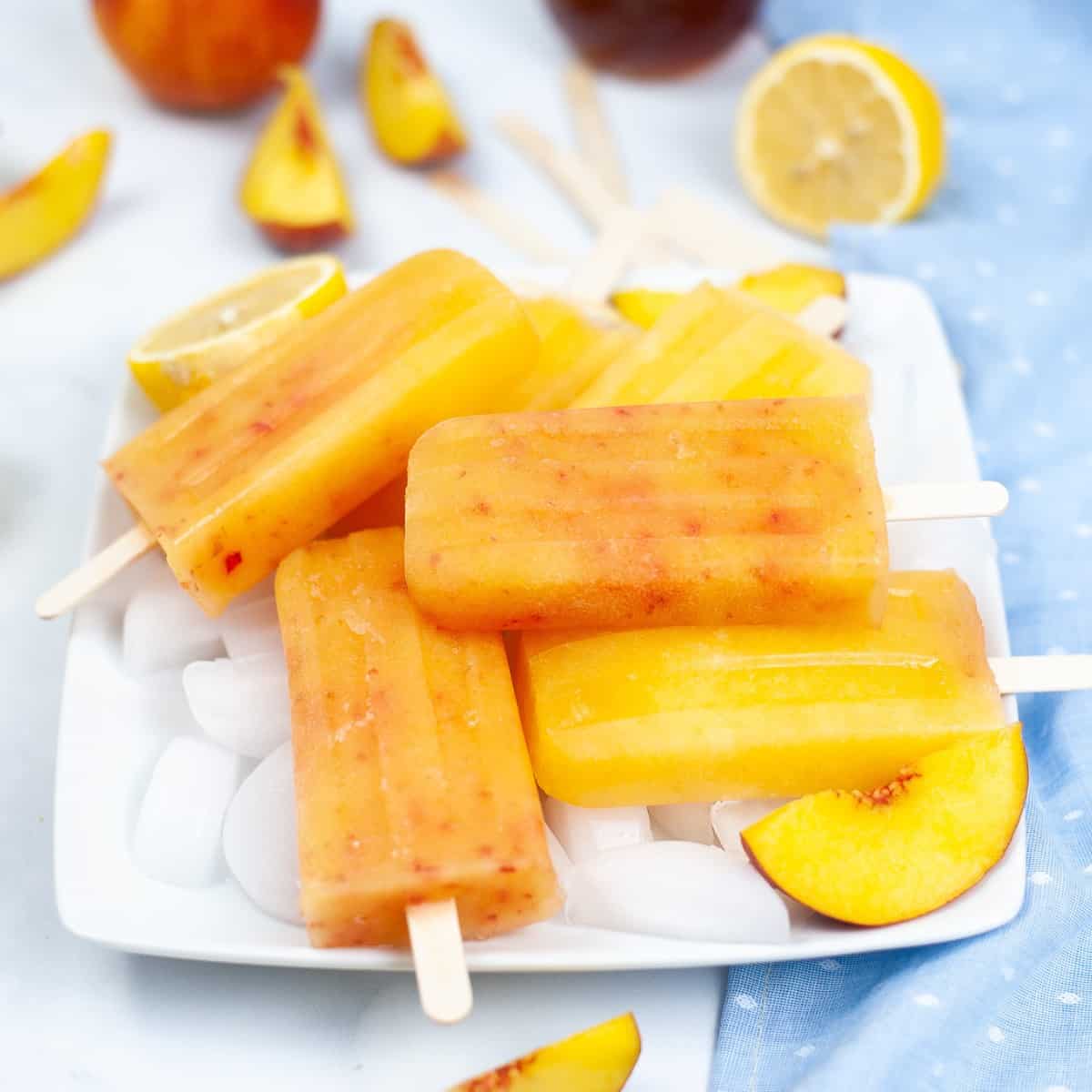 Pile of Peach Lemonade Popsicles on a plate of ice.