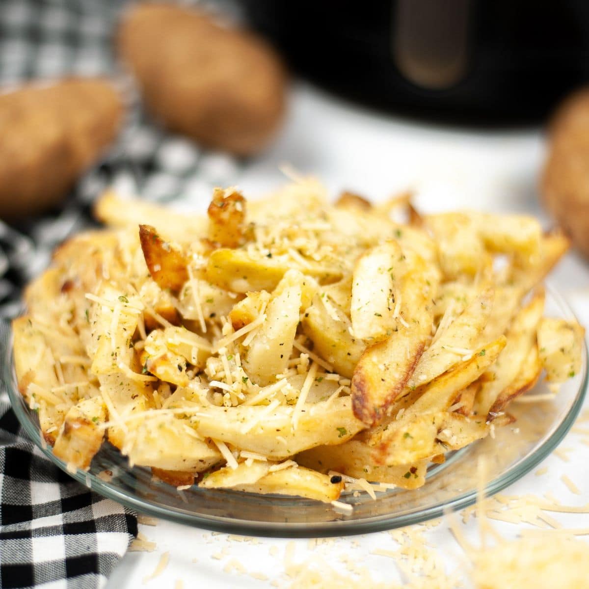 Fries topped with parmesan cheese on a glass plate.
