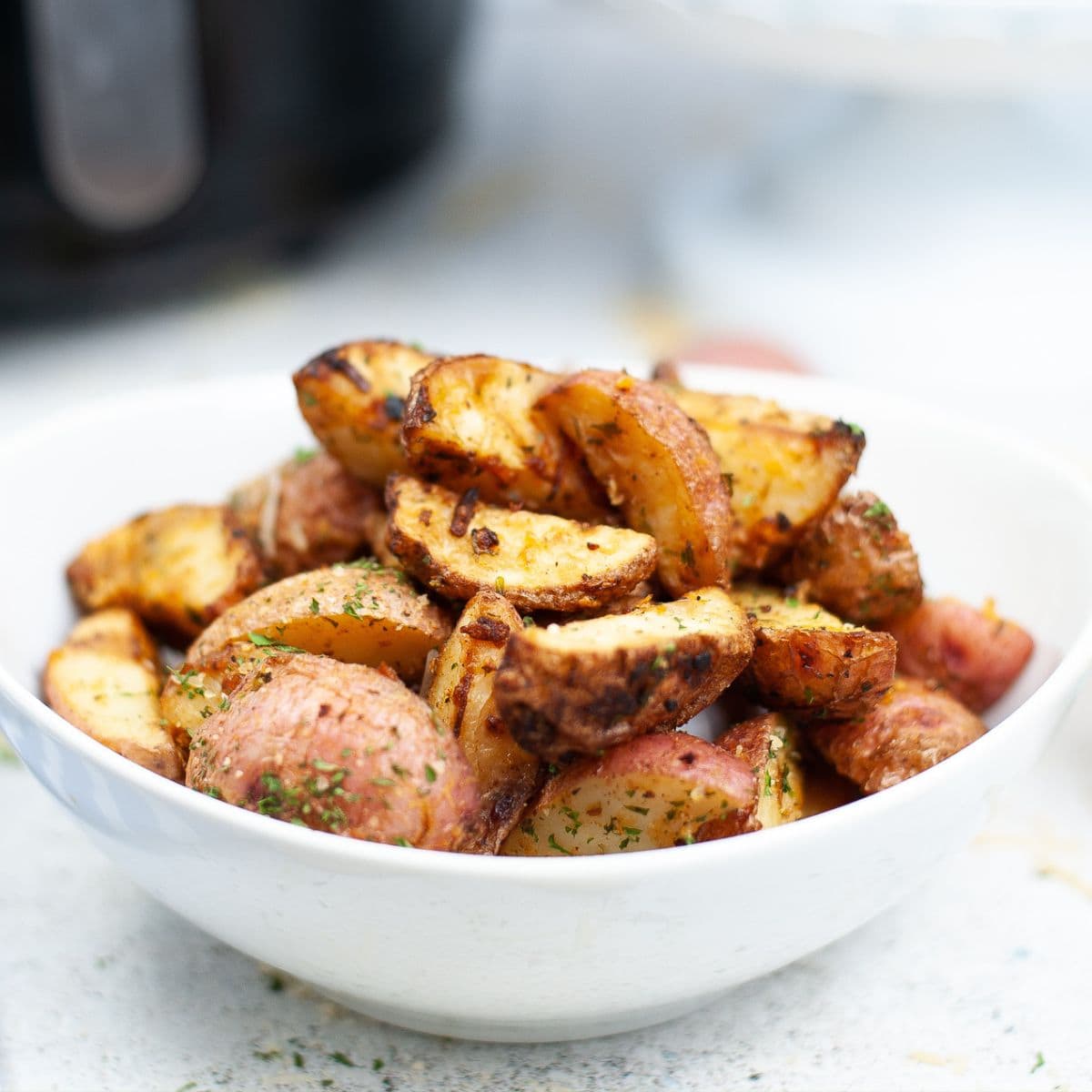 Small white bowl of roasted potatoes.