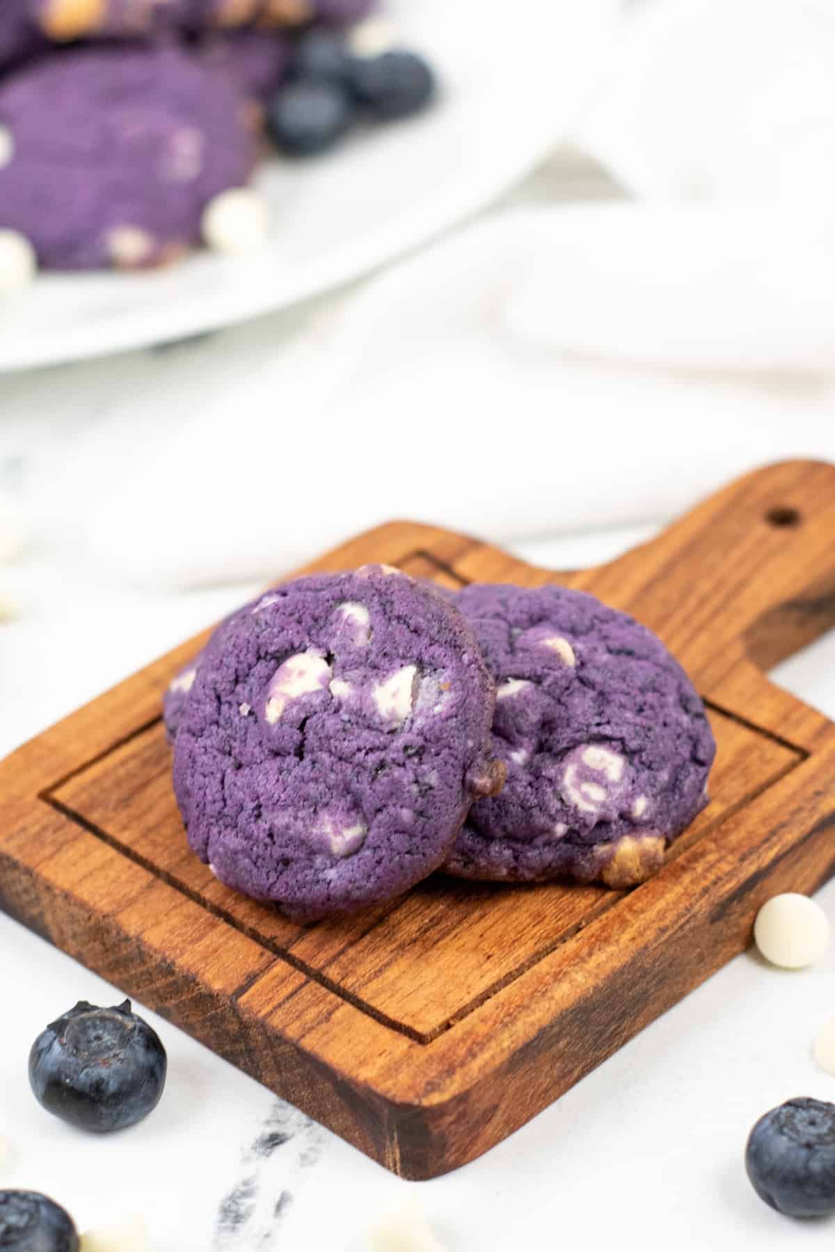 Two cookies sitting on a wooden cutting board.