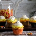 Candy corn cupcakes with cady eyes sitting on a wooden table.