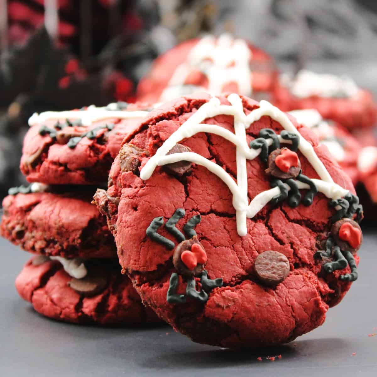 Stacked of red velvet cookies with spider and spider web decorations.