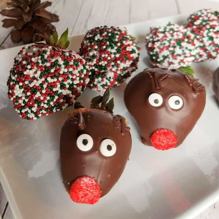 Christmas themed chocolate strawberries sitting on a white plate.