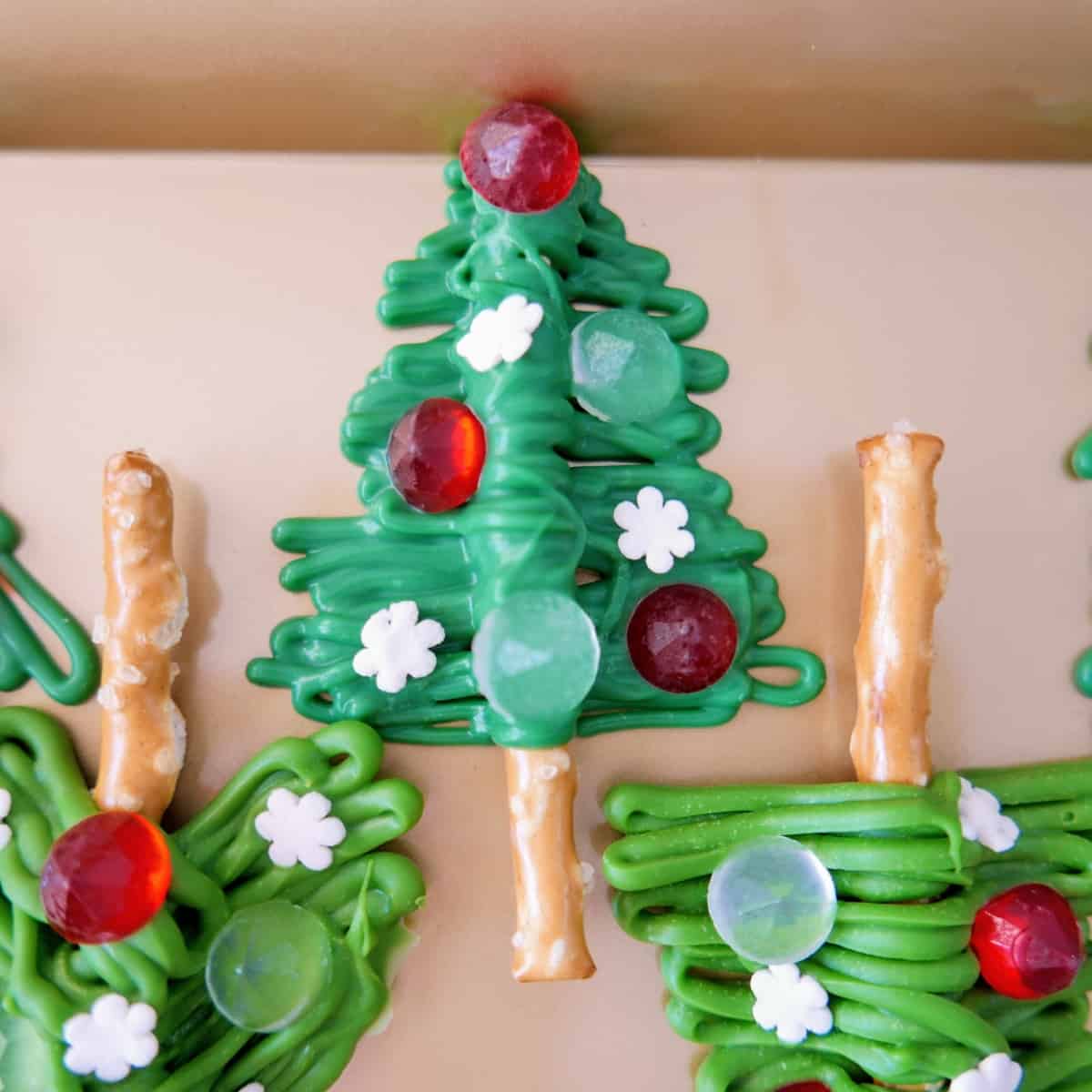 Pretzels decorated with green candy melts and candy gems to look like a Christmas tree.