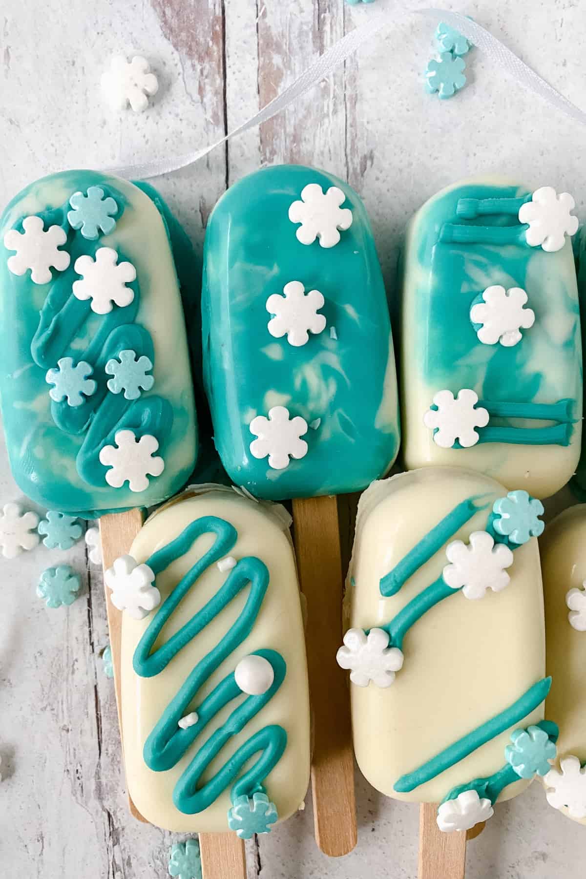 Cake pops coated with white almond bark topped with snowflake sprinkles.