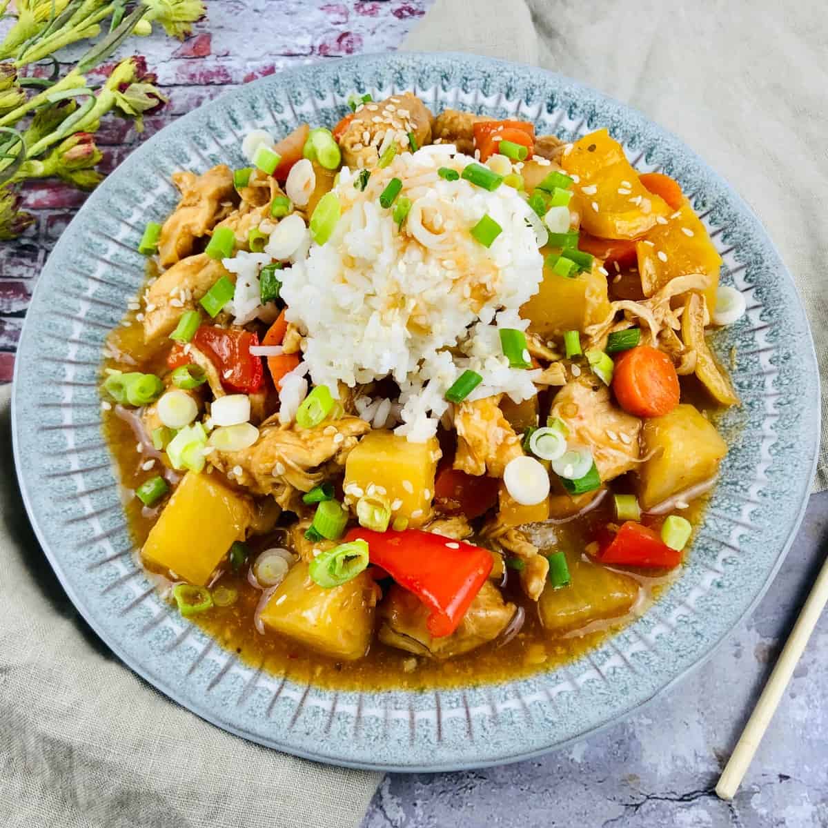 Sweet and sour chicken garnished with chopped green onion and sesame seeds.