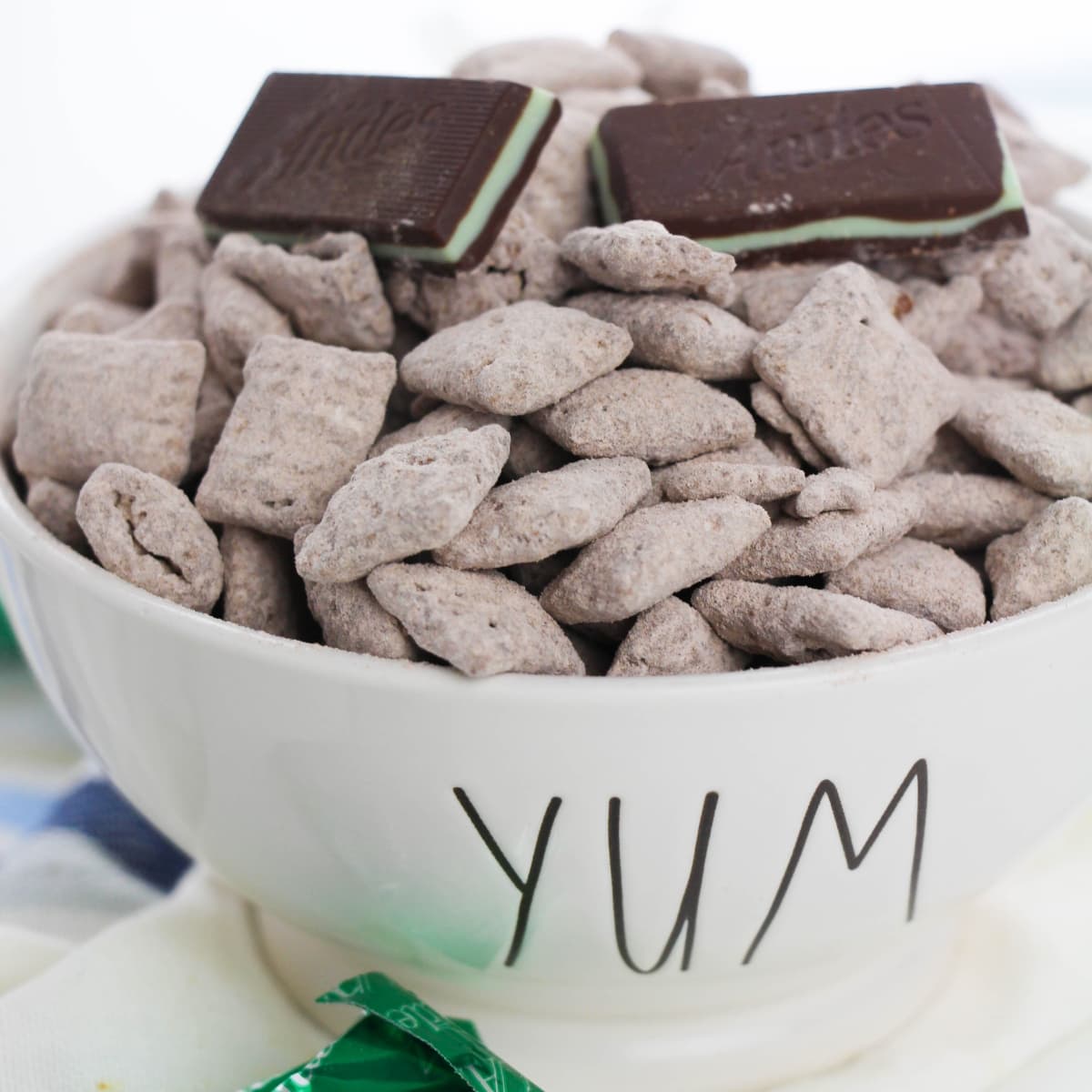 Chex cereal covered with chocolate in a white bowl.