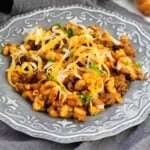 A plate of Chili Mac topped with shredded cheese.