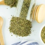 Jar spilling herb mixture onto a white countertop.