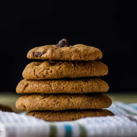Gluten free chocolate chip cookies stacked on a table.