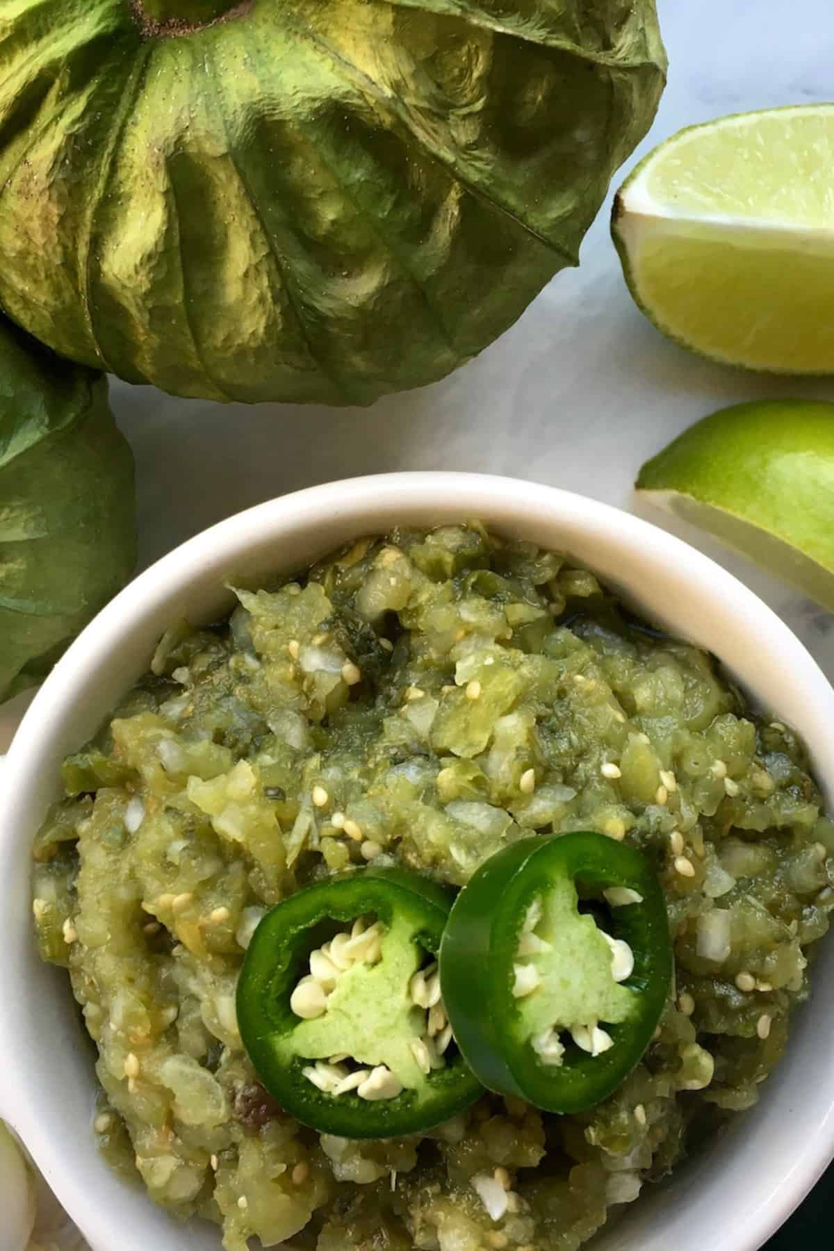 A bowl of salsa verde with veggies on the sides.