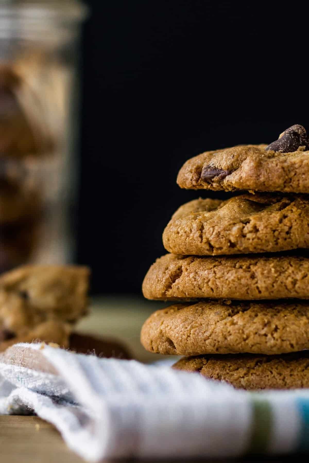 A stack of chocolate chip cookies sitting on a cloth.