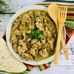 Bowl of Pork with Hatch Chile Salsa Verde with wooden utensils.