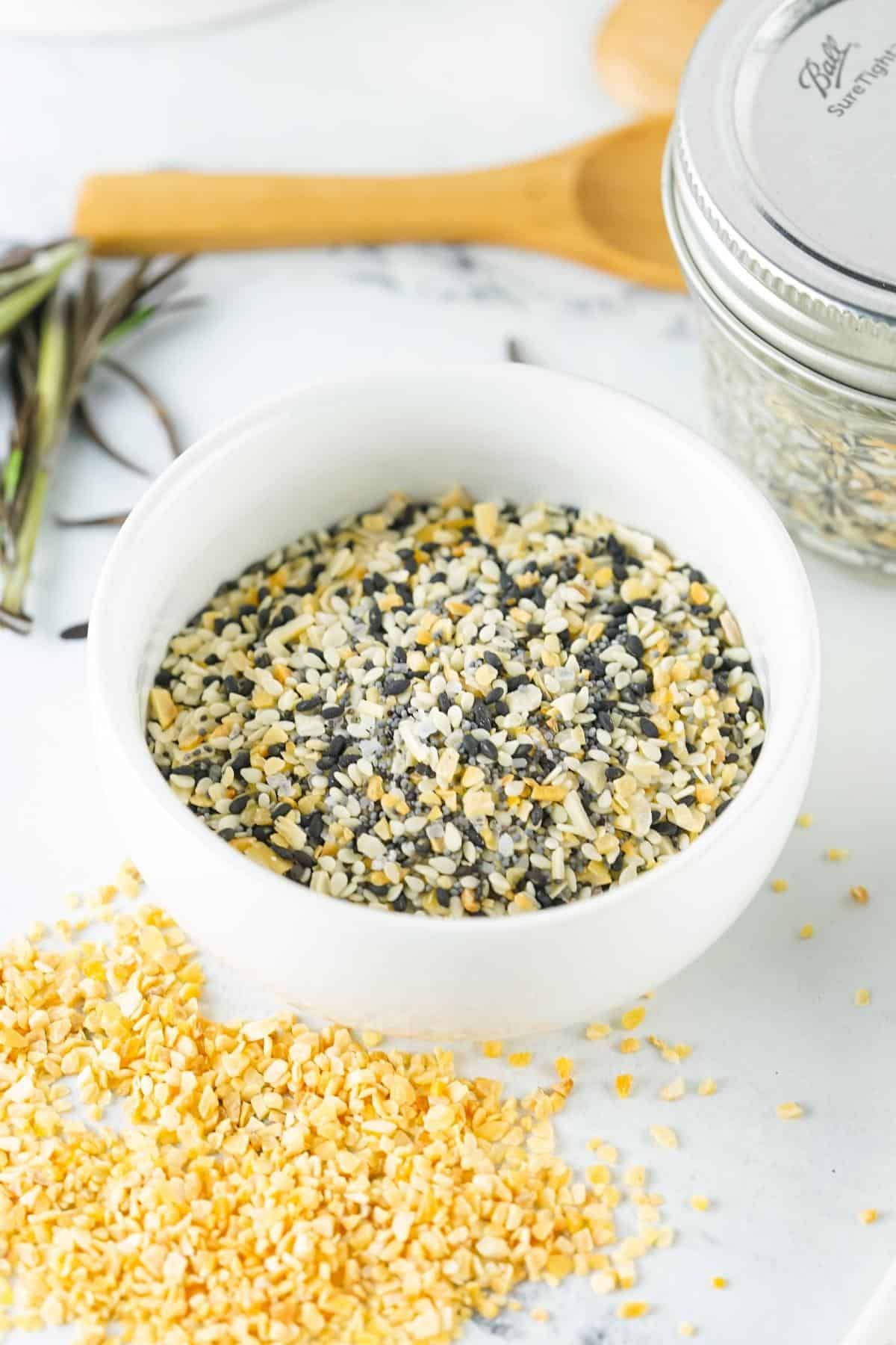 Black, white, and yellow bagel Seasoning mixture on a white bowl.