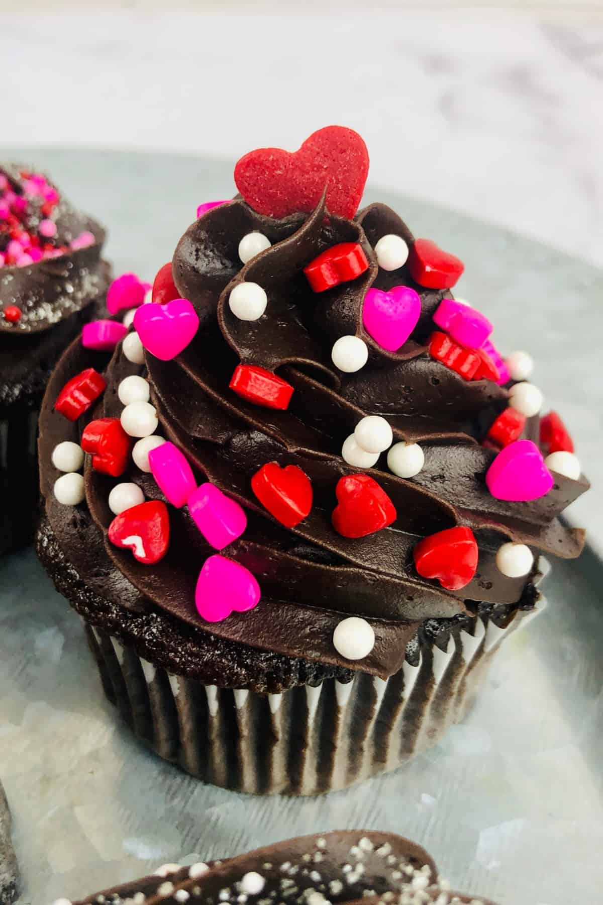 Chocolate Cupcake with chocolate frosting and topped with heart sprinkles.
