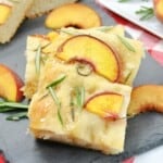 Two stacks of focaccia bread with peaches and rosemary.