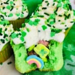 Green cupcakes filled with Lucky Charm marshmallows topped with white frosting.