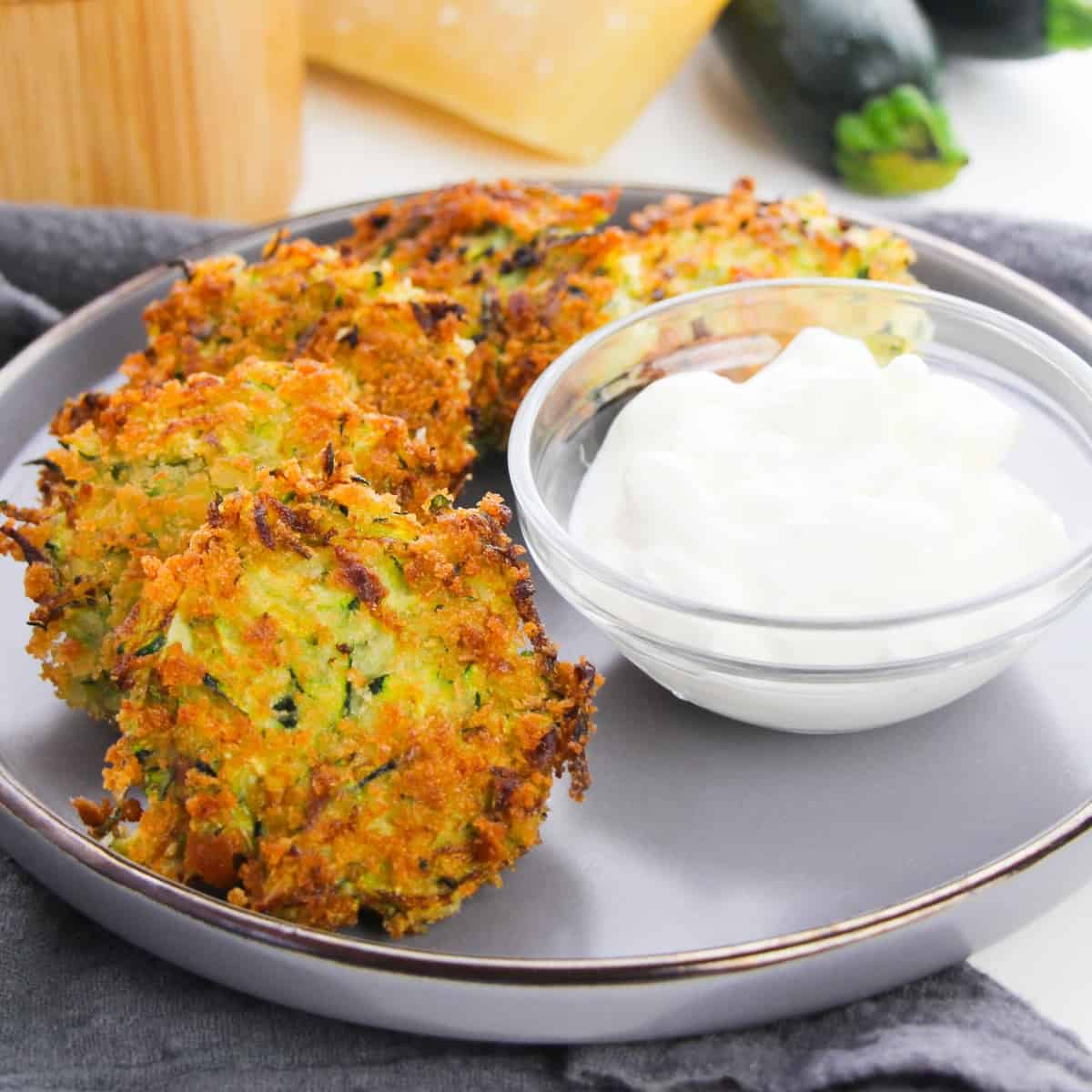 Zucchini Fritters and white sauce on a plate.