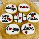 Cookies decorated with red hearts and black words like "always" and "love."