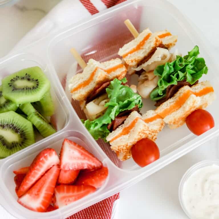 Turkey club kabobs in a bento box with fruit.