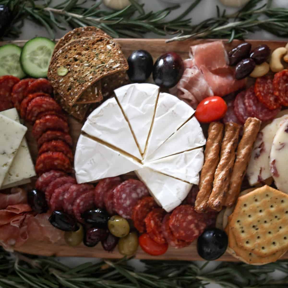 Christmas Charcuterie Board including meat, cucumbers, crackers, and cheese.