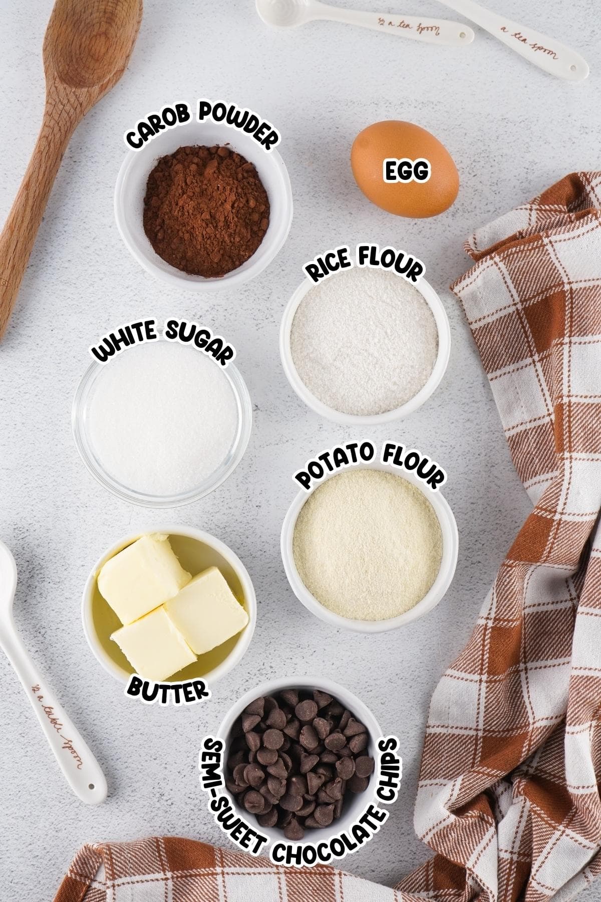 Ingredients for chocolate chip cookies including rice flour, potato flour, and carob powder sitting on a countertop.