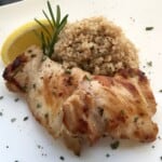Plate of Chicken Thighs with rosemary and sliced lemon on the side.
