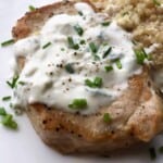 Boneless pork chops with quinoa on the side sitting on a white plate.