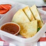 Lunch container of spinach pizzadillas with marinara.