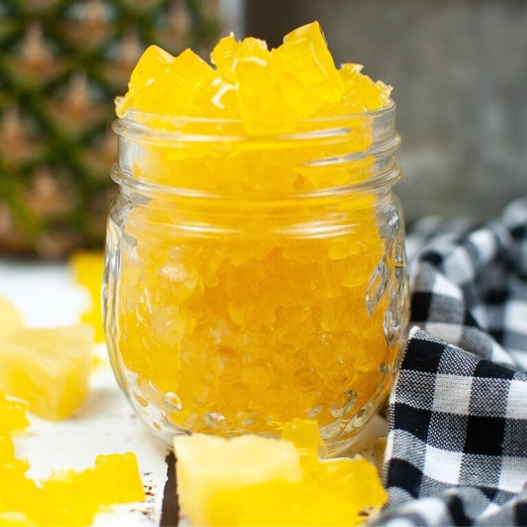 Mason jar overflowing with bright yellow Pineapple Gummy Bears.
