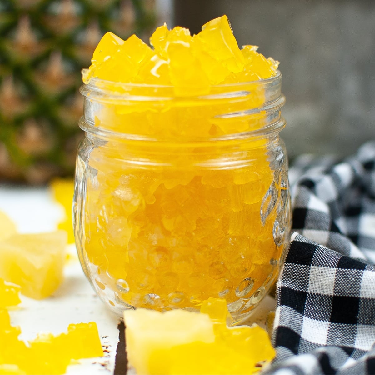 Mason jar overflowing with bright yellow Pineapple Gummy Bears.