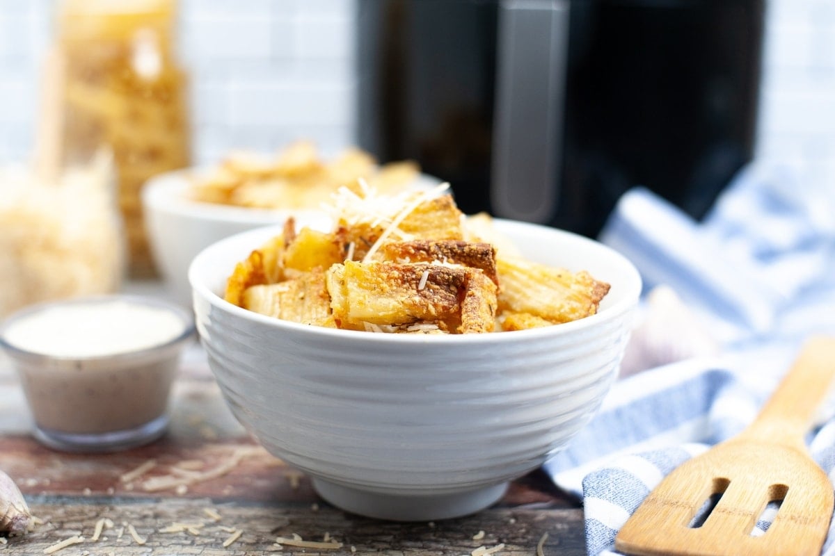 A white bowl of pasta chips sitting on a wooden table.