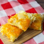 Garlic Bread Rolls with melted cheese on top on a wooden board.
