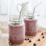 Mason jars of Acai Smoothie with metal straws.