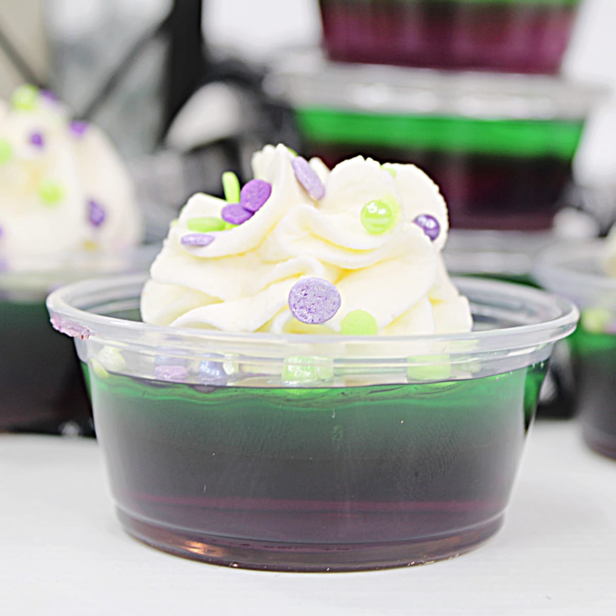 Hulk Jello Shots topped with whipped cream and sprinkles.