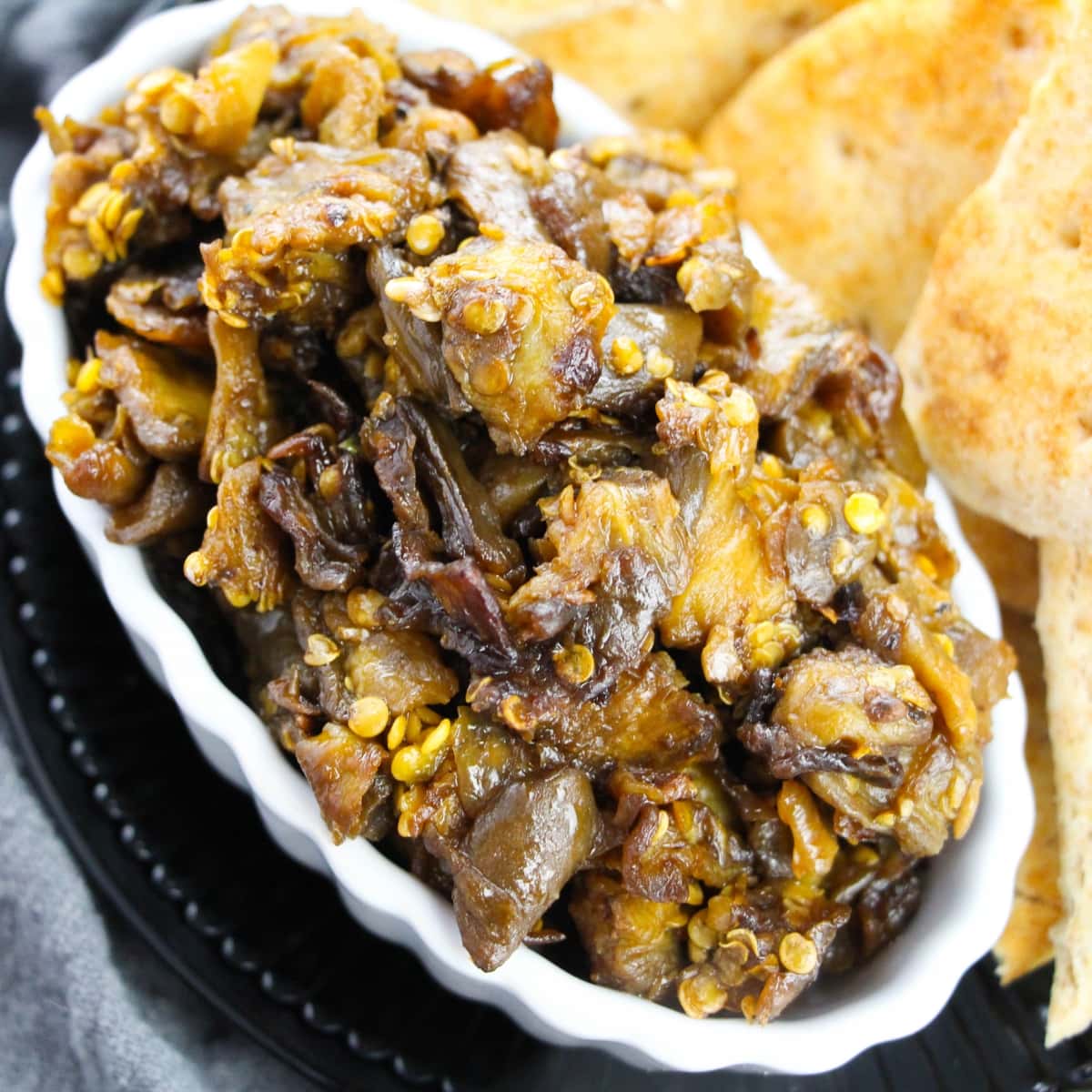 White, oblong bowl of eggplant salsa dip.