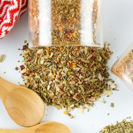 Spilled seasoning mixture on a white countertop with wooden spoons.