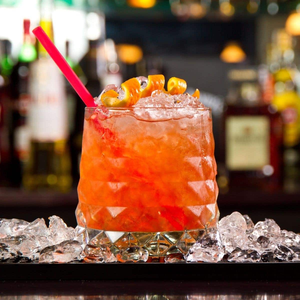 Bohemian Cocktail in a rocks glass topped with an orange peel and a straw.