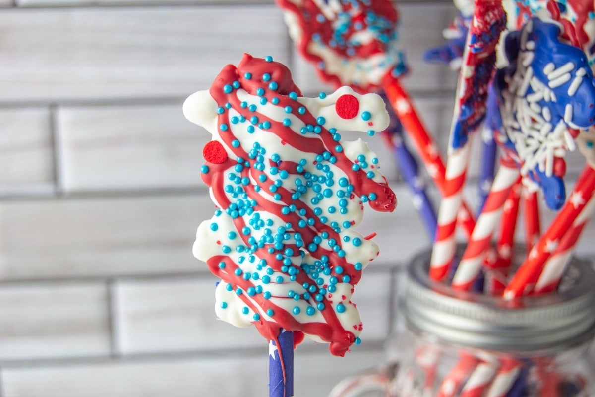 A white and red chocolate lollipop with sprinkles.