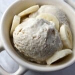 White mug filled with banana yogurt with sliced bananas.