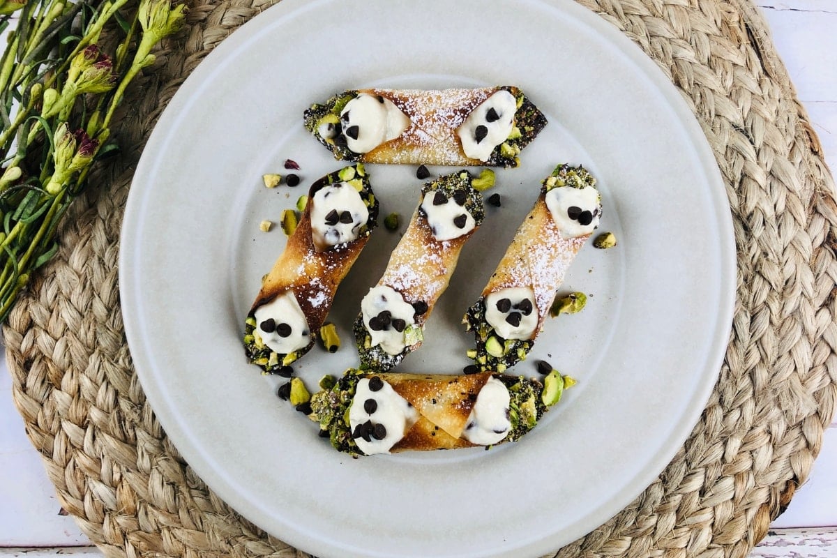 White plate of Mini Cannoli topped with mini chocolate chips.