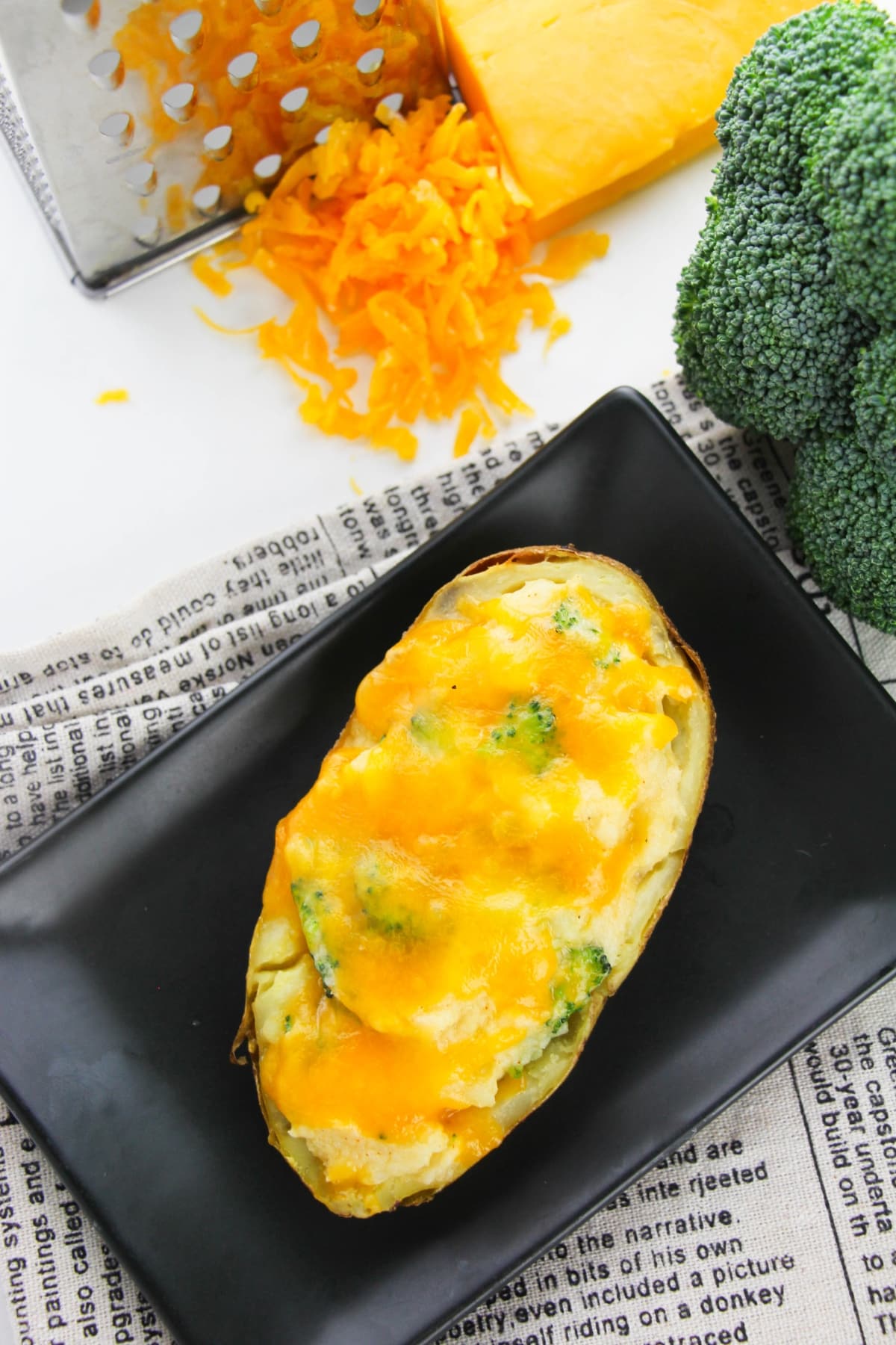 Two baked potatoes with cheddar cheese and broccoli on a background.