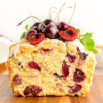 Cherry Loaf with an end sliced off and topped with glaze and fresh cherries.