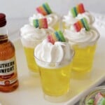 Five Jello Shots with cool whip and rainbow candy on top.