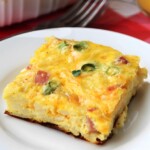 A slice of baked egg with ham on a white plate.