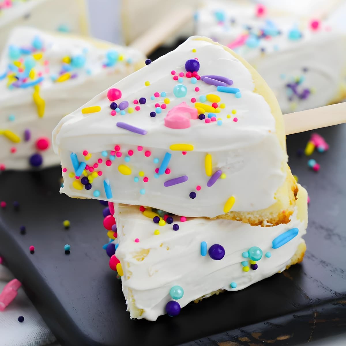 A pile of Cheesecake with sprinkles on a wooden board.