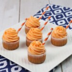 Five Cupcakes With Orange Frosting on a white plate.